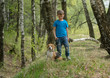 A boy seven years old walking in the woods with a Beagle