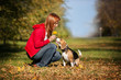 Girl playing with her  dog in autumn park